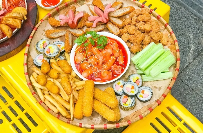 Mẹt ăn vặt mẹt tre gồm bánh gạo cay kimbab chiên khoai tây chiên phô mai que cá viên và xúc chiên xù