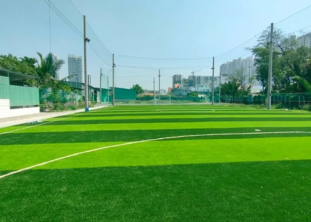 Sân bóng đá cỏ nhân tạo ngoài trời rộng rãi, xanh mướt với hệ thống đèn chiếu sáng và lưới quây