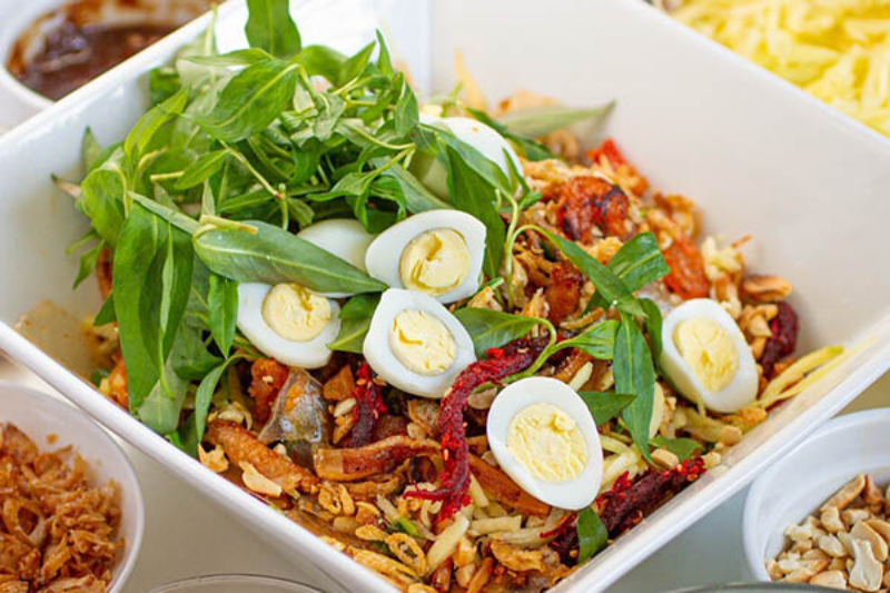 Món bánh tráng trộn đầy đặn topping trứng cút rau răm khô bò tại khu ăn vặt
