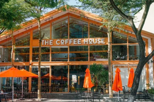 Không gian mặt tiền cửa hàng The Coffee House với thiết kế khung kính lớn và tông màu cam đặc trưng