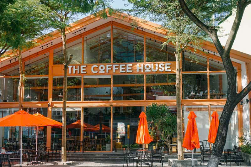 Không gian mặt tiền cửa hàng The Coffee House với thiết kế khung kính lớn và tông màu cam đặc trưng