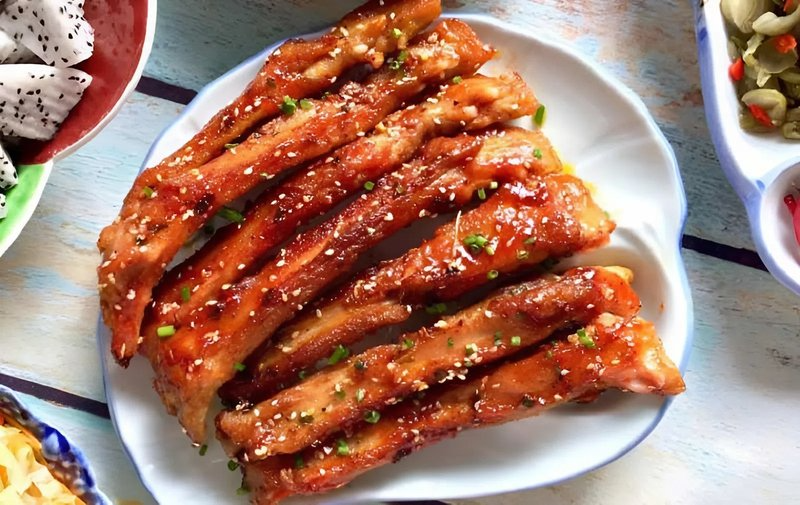 Đĩa sườn heo nướng BBQ vàng óng, sốt đặc, rắc vừng trắng và hành lá thái nhỏ