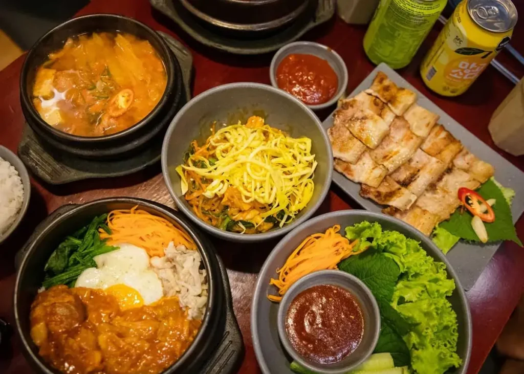Bàn tiệc ẩm thực Hàn Quốc gồm cơm trộn bibimbap, thịt ba chỉ nướng và canh kim chi