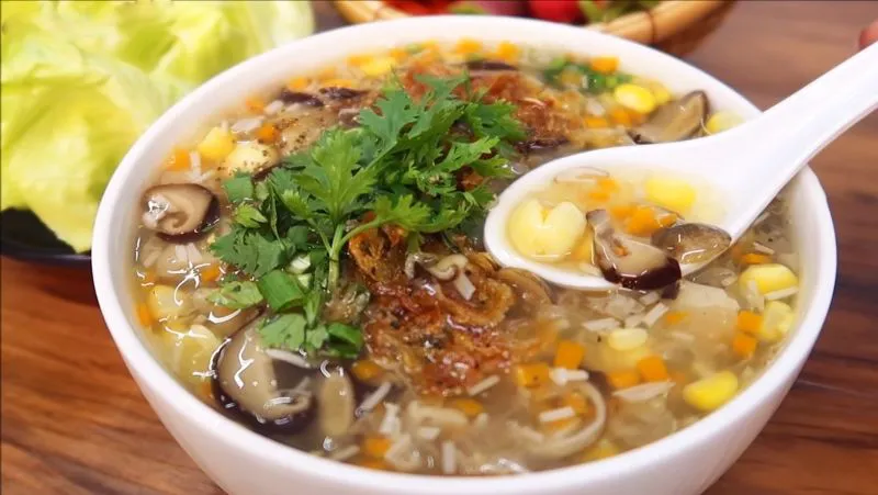 Bát súp cua nóng hổi với thịt cua, trứng, bắp và nấm hương. Phía trên rắc rau mùi và hành phi thơm phức. Bên cạnh là rổ rau xà lách tươi xanh